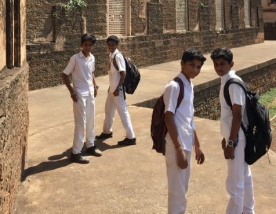 Schoolboys walking through the ruins of the Mahmud Gawan madrasa, Bidar, India